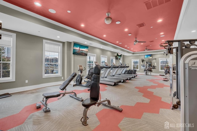 gym with a raised ceiling and light carpet