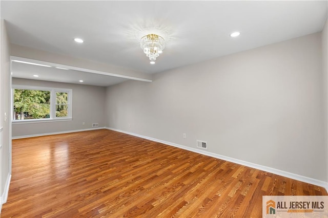 unfurnished room featuring beam ceiling, a chandelier, and light hardwood / wood-style flooring