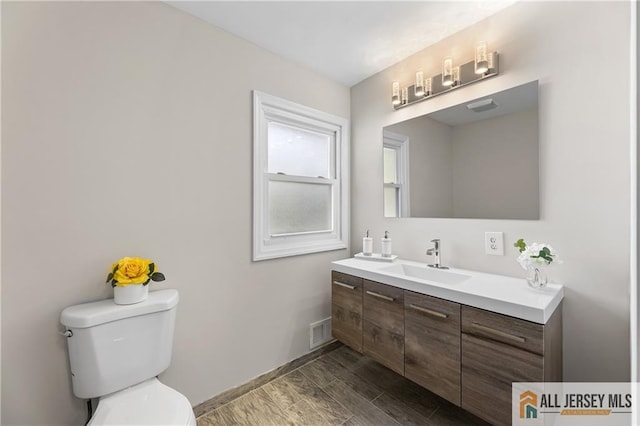 bathroom with hardwood / wood-style flooring, vanity, and toilet