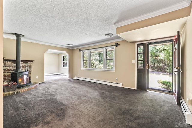 unfurnished living room with a baseboard heating unit, a healthy amount of sunlight, and a wood stove