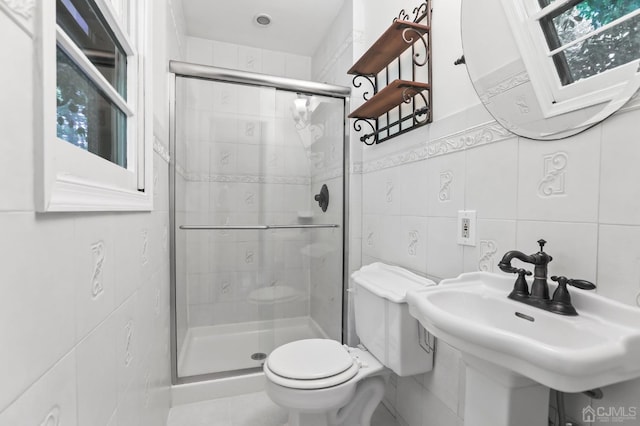 bathroom featuring a shower with door, sink, tile walls, and toilet