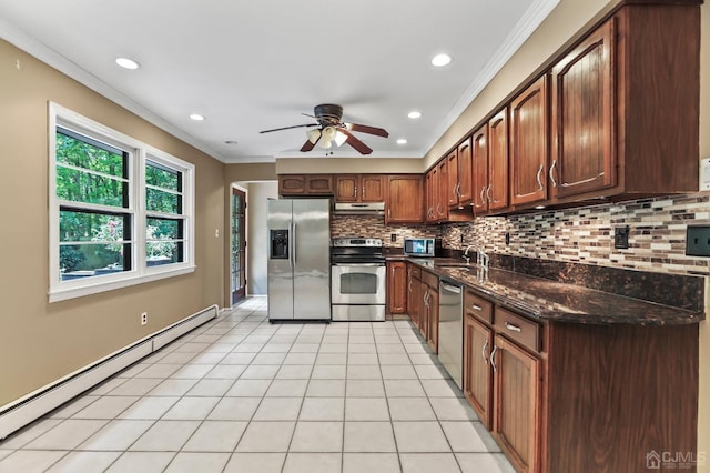 kitchen with sink, dark stone countertops, stainless steel appliances, ornamental molding, and a baseboard radiator