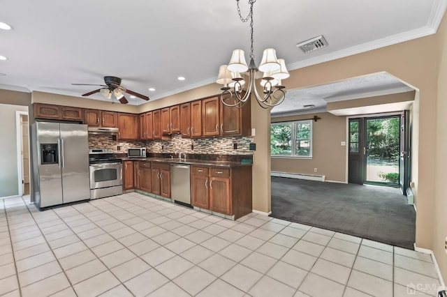 kitchen featuring pendant lighting, a baseboard radiator, decorative backsplash, light colored carpet, and stainless steel appliances