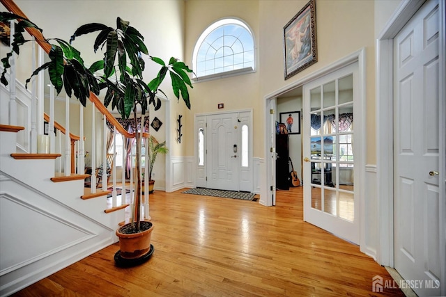 2 Eddie Ct, South Brunswick, NJ 08810 - entrance foyer with plenty of natural light, light wood-style flooring, a wainscoted wall, a high ceiling, and stairs