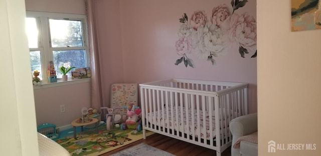 bedroom featuring a nursery area and wood finished floors