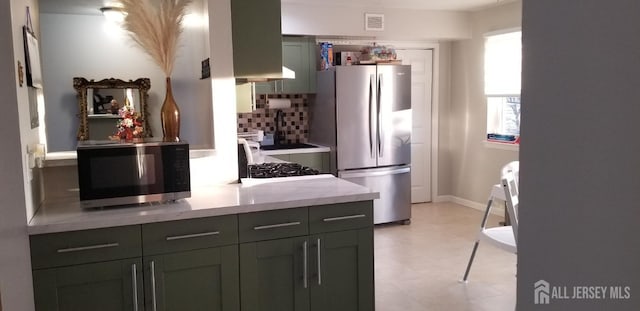 kitchen featuring appliances with stainless steel finishes, visible vents, backsplash, and baseboards