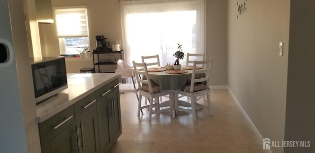 dining space featuring light tile patterned flooring and baseboards