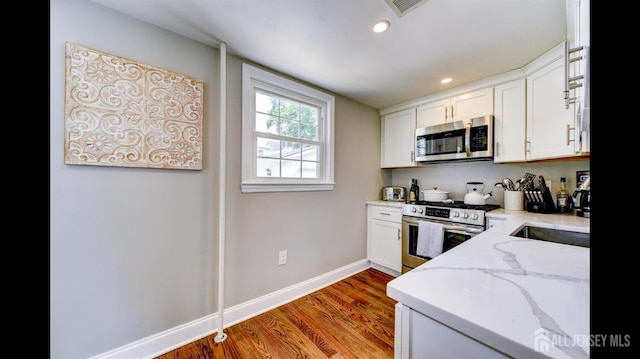 3 Mayfield Pl, Metuchen, NJ 08840 - kitchen featuring appliances with stainless steel finishes, light stone countertops, white cabinetry, light wood-type flooring, and recessed lighting