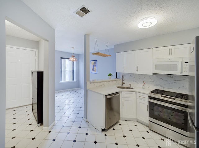 kitchen featuring visible vents, a sink, stainless steel appliances, light countertops, and white cabinets