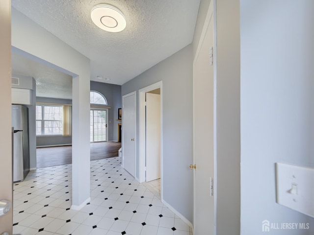 corridor with a textured ceiling and baseboards