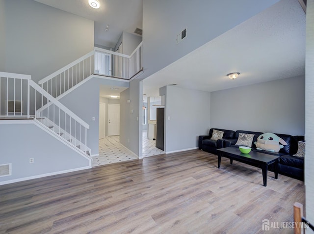 living area with visible vents, stairs, baseboards, and wood finished floors