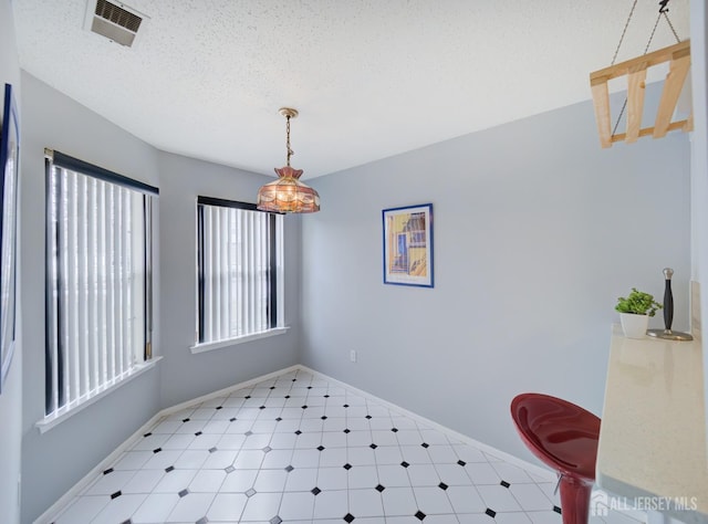 dining space featuring baseboards, light floors, visible vents, and a textured ceiling