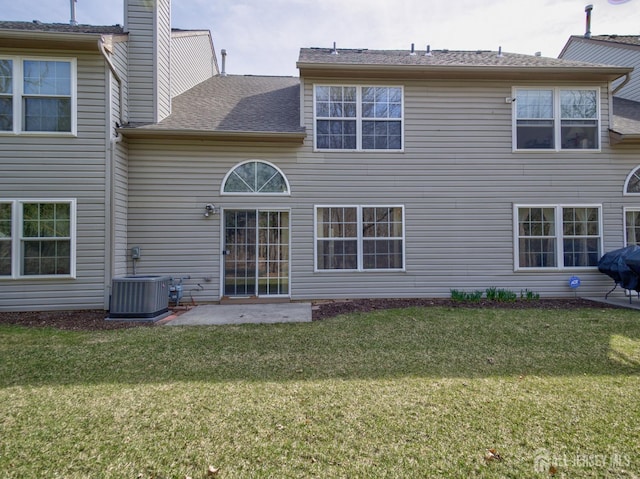 rear view of house featuring a patio area, central air condition unit, a lawn, and roof with shingles