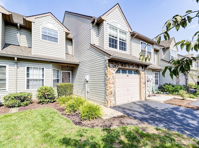 view of property featuring aphalt driveway, stone siding, a shingled roof, and a garage