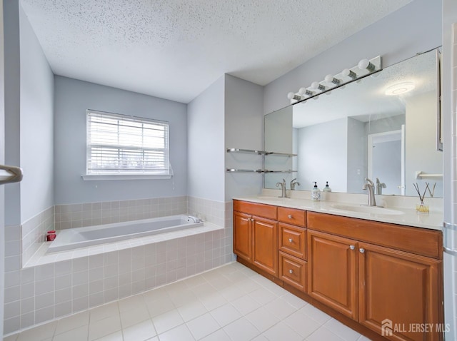 full bath featuring a textured ceiling, a garden tub, and a sink