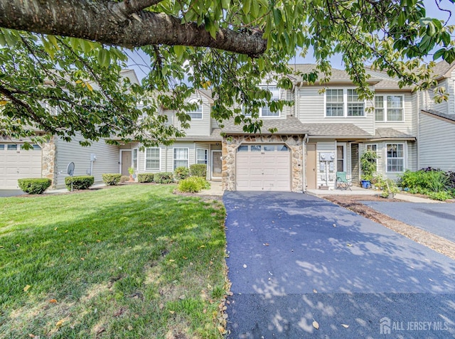 view of property featuring a front lawn, a garage, stone siding, and driveway