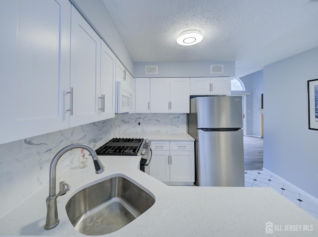 kitchen with stainless steel appliances, white cabinetry, and light countertops