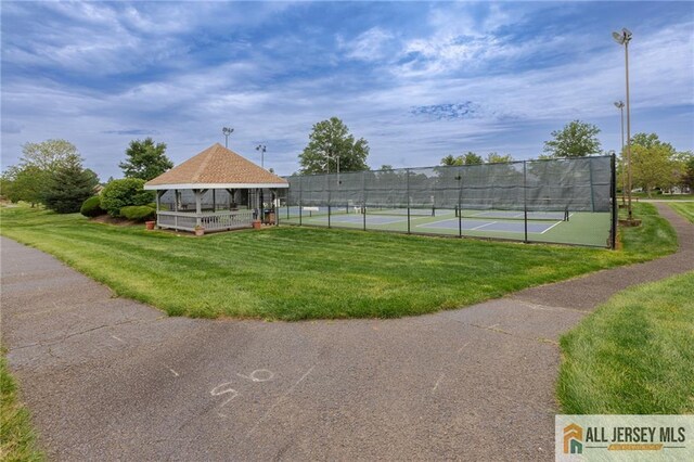 view of home's community with a tennis court, a gazebo, a yard, and fence