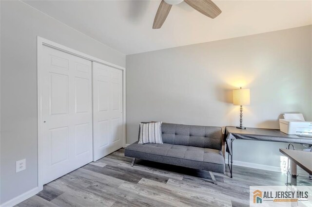 living area featuring light wood finished floors, baseboards, and a ceiling fan