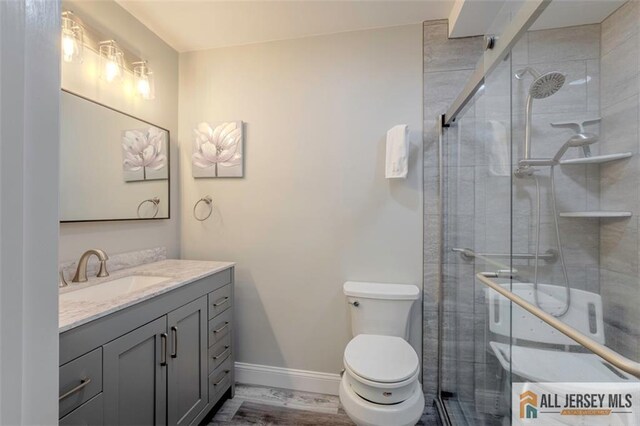 full bathroom featuring toilet, a stall shower, vanity, and baseboards