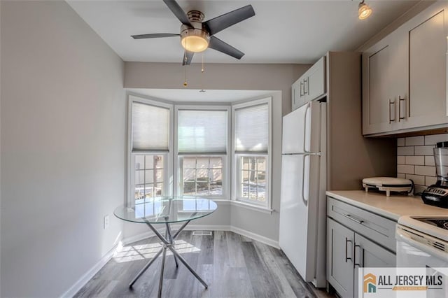 kitchen with ceiling fan, tasteful backsplash, wood finished floors, light countertops, and white appliances
