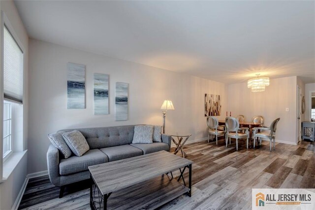 living room featuring a chandelier, baseboards, and wood finished floors