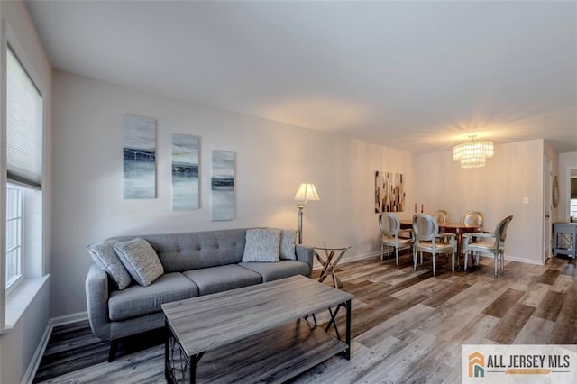 living area featuring light wood-type flooring, baseboards, and a notable chandelier