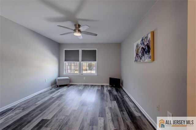 spare room featuring ceiling fan, dark wood-style flooring, and baseboards