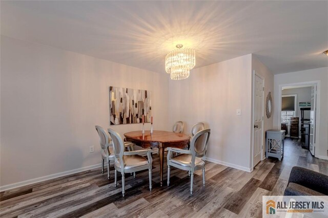 dining room featuring a notable chandelier, baseboards, and wood finished floors