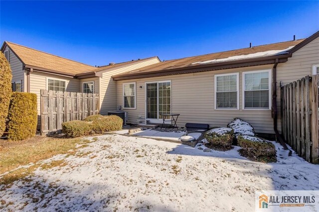 snow covered rear of property featuring fence