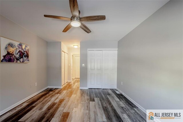 unfurnished bedroom featuring wood finished floors, a ceiling fan, and baseboards