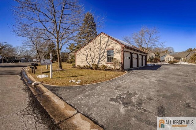 view of side of property with a residential view, driveway, and a lawn