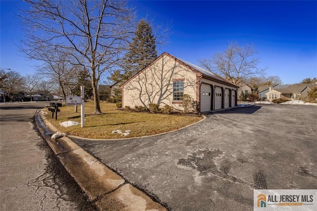view of side of home featuring a lawn, aphalt driveway, and a garage