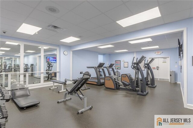 gym with baseboards, visible vents, and a drop ceiling