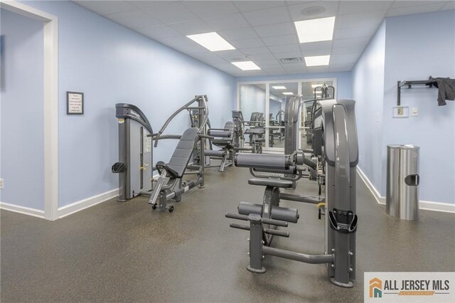 exercise room with a paneled ceiling and baseboards