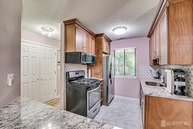 19 Carriage Pl, Edison, NJ 08820 - kitchen featuring stainless steel appliances, brown cabinetry, light stone counters, and a textured ceiling