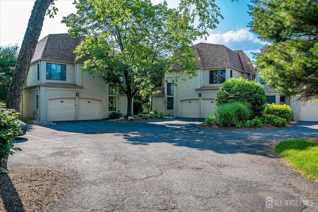 19 Carriage Pl, Edison, NJ 08820 - tudor home with stucco siding, a garage, a shingled roof, driveway, and mansard roof
