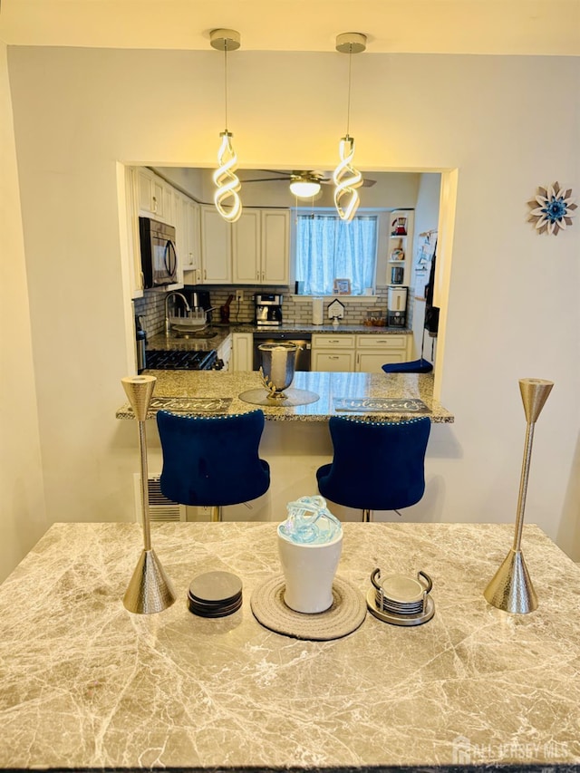 45 Marina View Dr, Sewaren, NJ 07077 - kitchen featuring black microwave, range, tasteful backsplash, dishwashing machine, and a kitchen bar