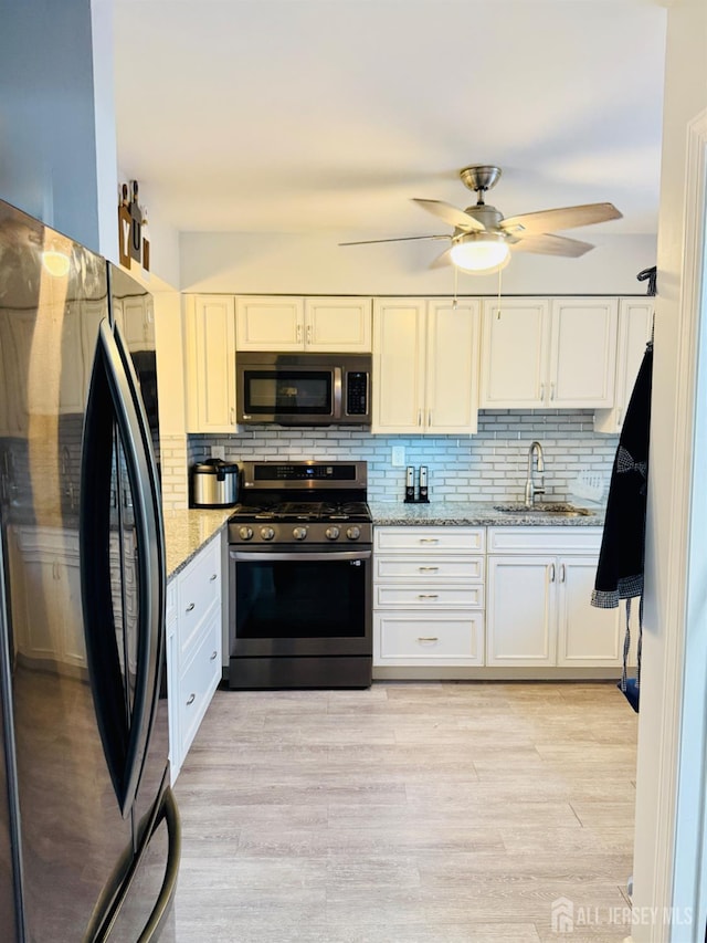 45 Marina View Dr, Sewaren, NJ 07077 - kitchen featuring appliances with stainless steel finishes, light stone countertops, tasteful backsplash, and white cabinets