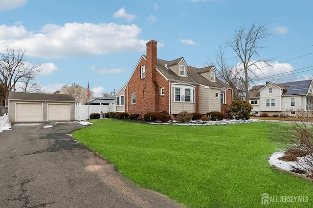 view of front of home with an outbuilding, a front yard, fence, and a detached garage