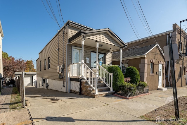 shotgun-style home with covered porch, an outdoor structure, and concrete driveway