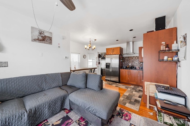 living room with ceiling fan with notable chandelier and light wood-type flooring