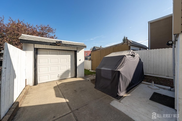 garage featuring fence and concrete driveway