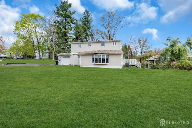 rear view of house featuring a lawn, a deck, cooling unit, stucco siding, and an attached garage