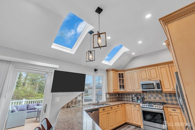 kitchen with a sink, appliances with stainless steel finishes, light brown cabinets, and a healthy amount of sunlight