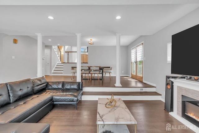 living area with recessed lighting, decorative columns, dark wood-style floors, and stairway