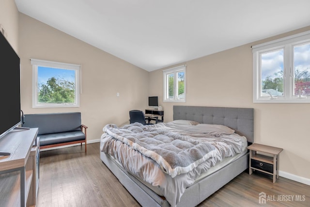 bedroom featuring wood finished floors, baseboards, and lofted ceiling