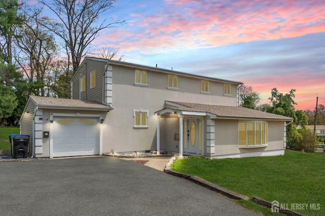 view of front facade featuring an attached garage, stucco siding, a yard, and driveway