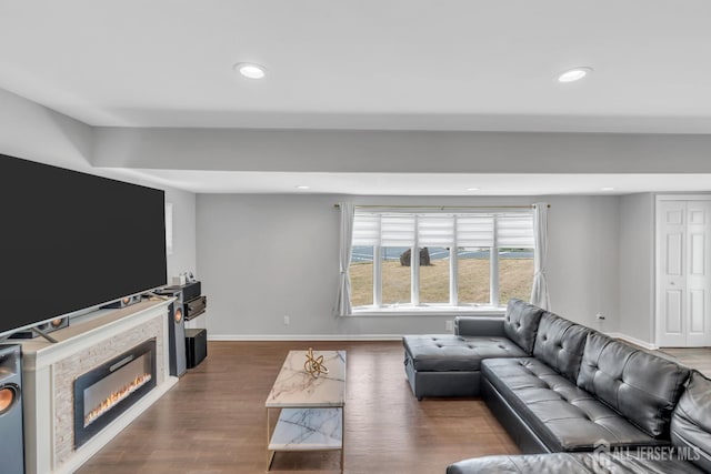 living room with a glass covered fireplace, baseboards, recessed lighting, and dark wood-style floors