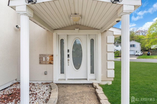 view of exterior entry featuring a yard and stucco siding